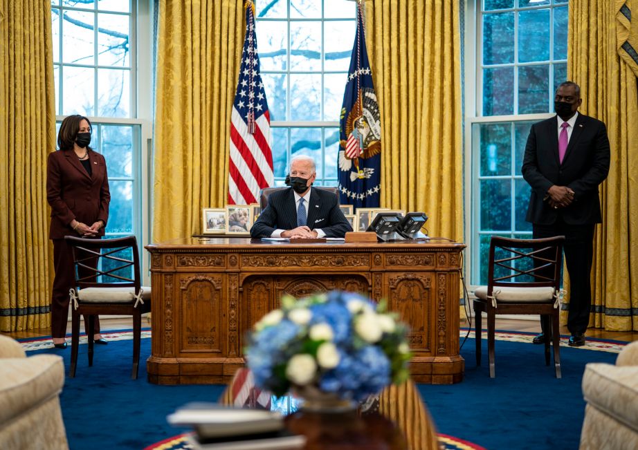 Vice President Kamala Harris, left, and Secretary of Defense Lloyd Austin, right, listen as President Joe Biden speaks before signing an Executive Order reversing the Trump era ban on transgender individuals serving in military, in the Oval Office of the White House, Monday, Jan. 25, 2021, in Washington. (AP Photo/Evan Vucci)