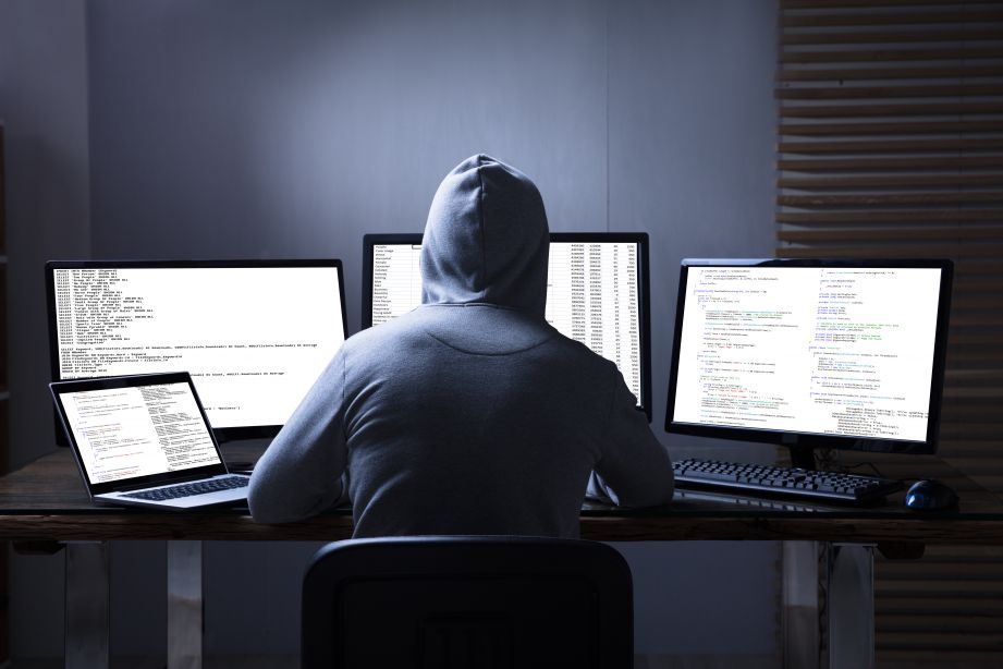 Hooded man on computer "hacking"