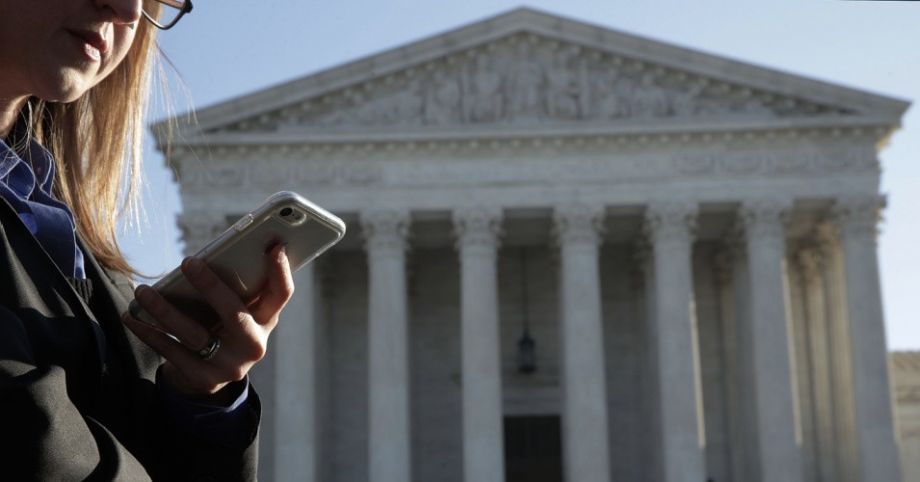 A woman checks her cell phone as she waits in line to enter the U.S. Supreme Court in Washington, D.C on November 29, 2017 for a hearing on Carpenter v. United States.