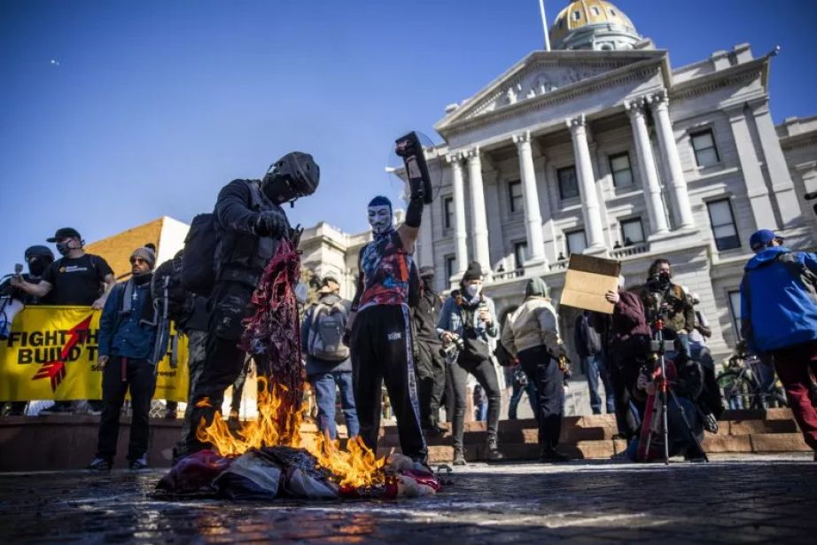 Protesters burn an American flag on the steps of the Colorado State Capitol on January 20, 2021.