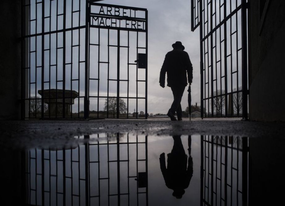 a man walks through the gate of the Sachsenhausen Nazi death camp with the phrase "Arbeit macht frei" (work sets you free) in Oranienburg, Germany, on International Holocaust Remembrance Day.