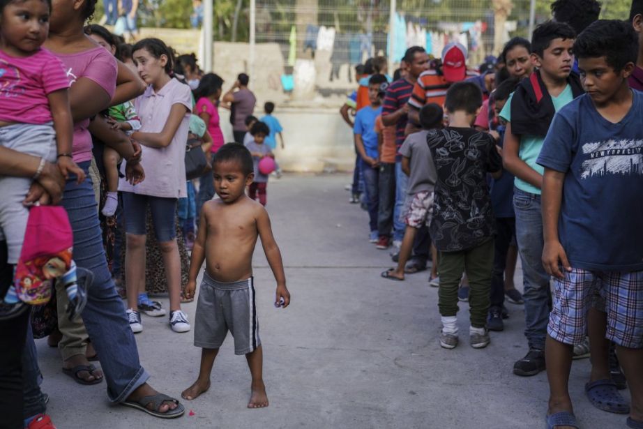 Migrants who were returned to Mexico under the Trump administration's "Remain in Mexico" program, wait in line to get a meal in an encampment near the Gateway International Bridge in Matamoros, Mexico.