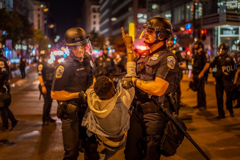 A large crowd of protestors confront police in a tense stand off.Police also arrest people.